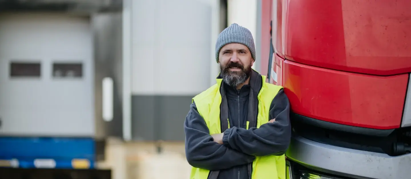 Man in a high-vis jacket standing in front of HGV smiling at the camera