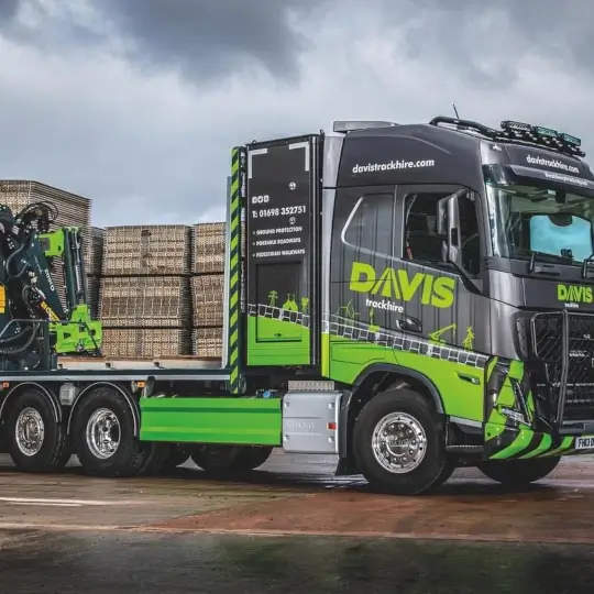 HGV parked in outside a warehouse, with crane claw on the back of it