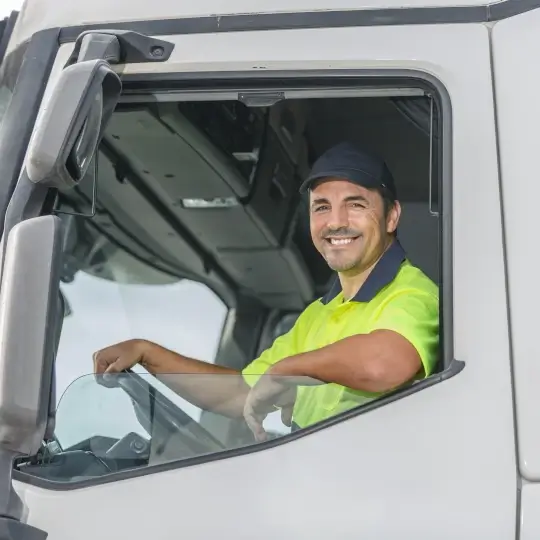 Man sitting in the front seat of a HGV, leaning out the window smiling at the camera