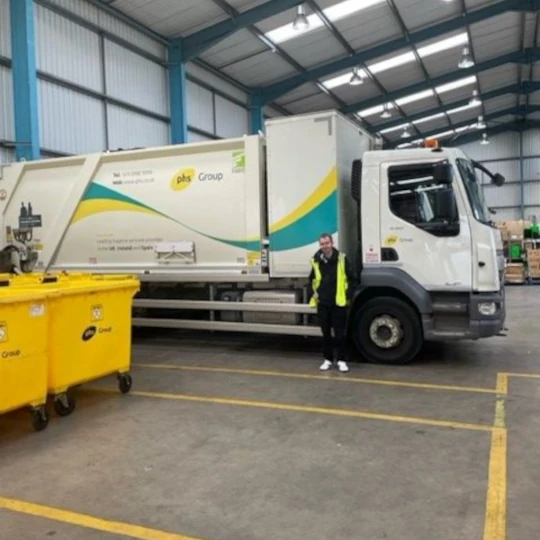 Man standing beside a white bin truck with phs Group logo on it