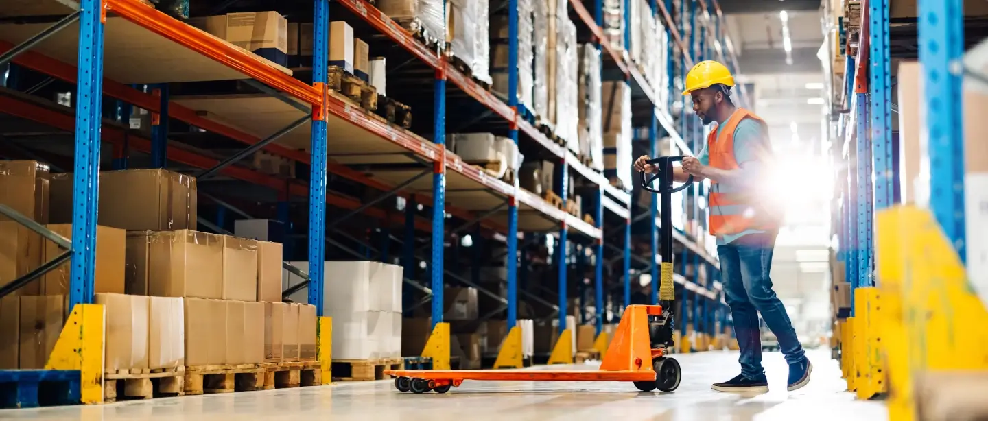A man using a pallet transporter in a warehouse