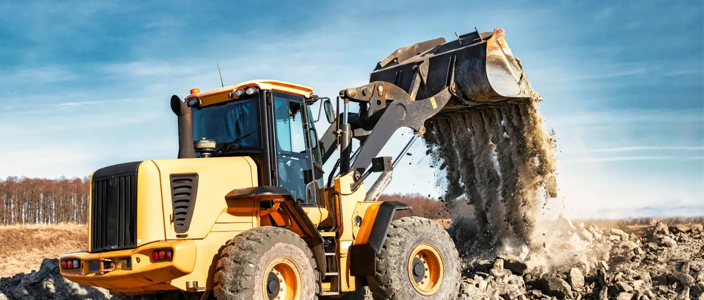 Yellow 180 degree excavator dumping a load on top of other material at a construction site