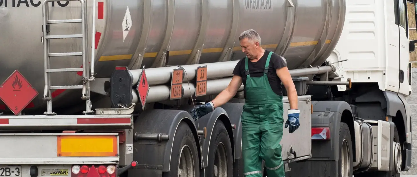Man in green overalls carrying out maintenance on a truck