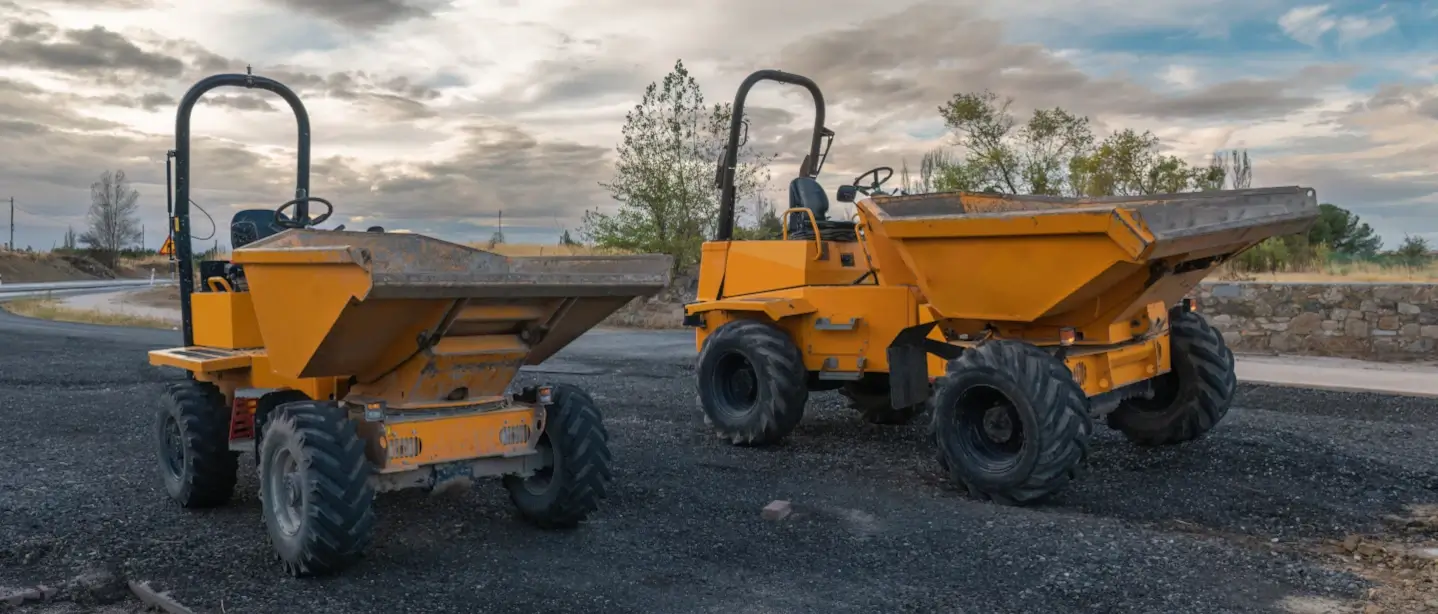 Two forward dumper trucks stood stationary at a construction site