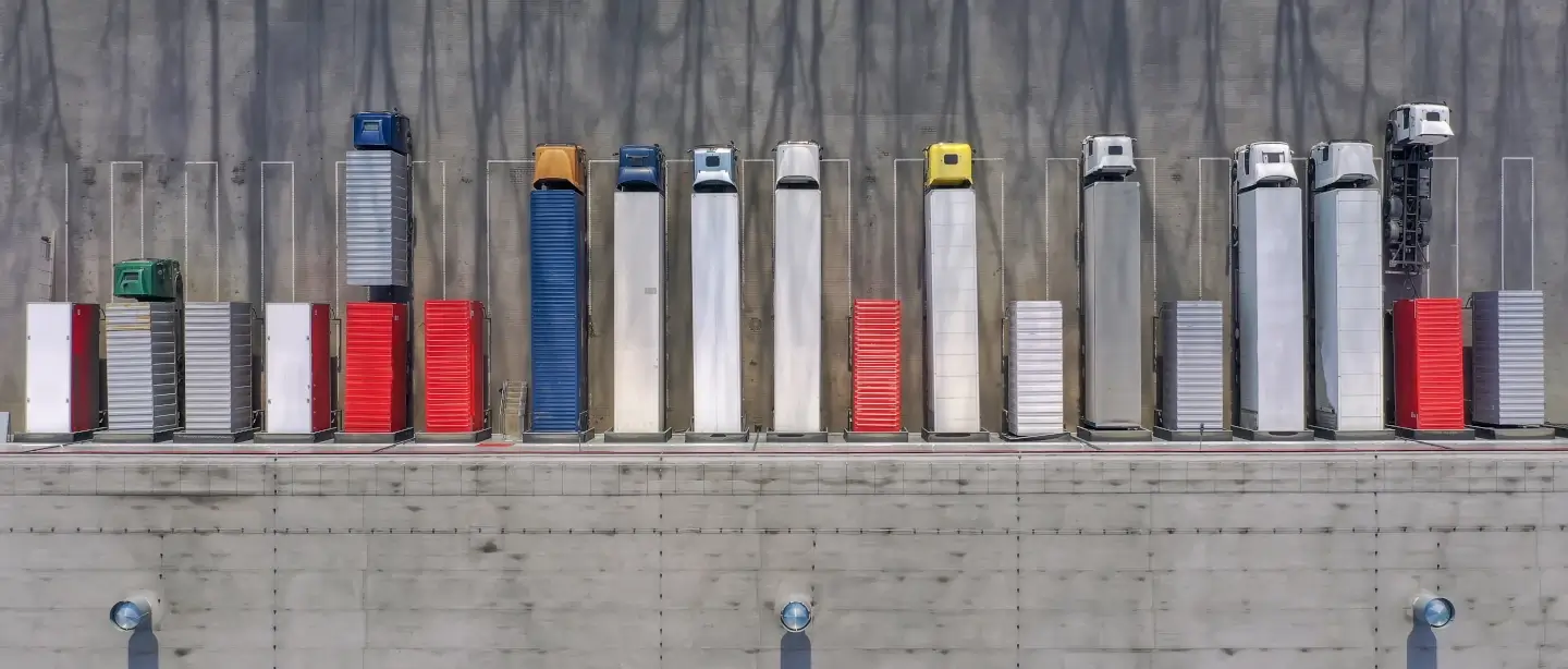 HGV's lined up parked in a warehouse from a birds eye view.