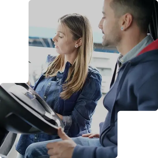 A man sitting in the drivers seat of a HGV with the door open, talking to a woman outside the HGV