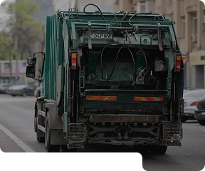 Green bin truck driving down the road