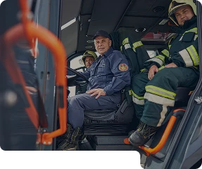 Three firefighters sitting in the front of a truck. looking at the camera