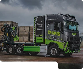 A green and black truck parked in a warehouse car park.