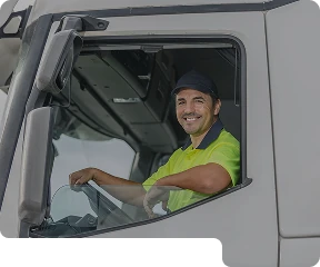 A man sitting in the front seat of a truck, looking out the window smiling at the camera